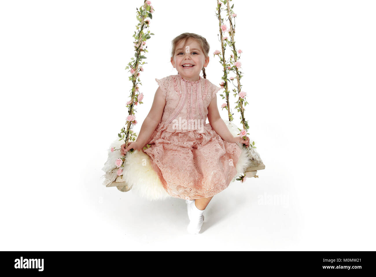 4 year old girl in pink dress sitting on decretive swing Stock Photo