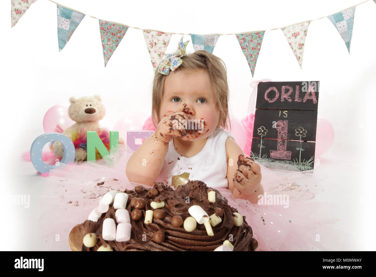 1 year old girl birthday party, cake smash, messy chocolate cake Stock Photo