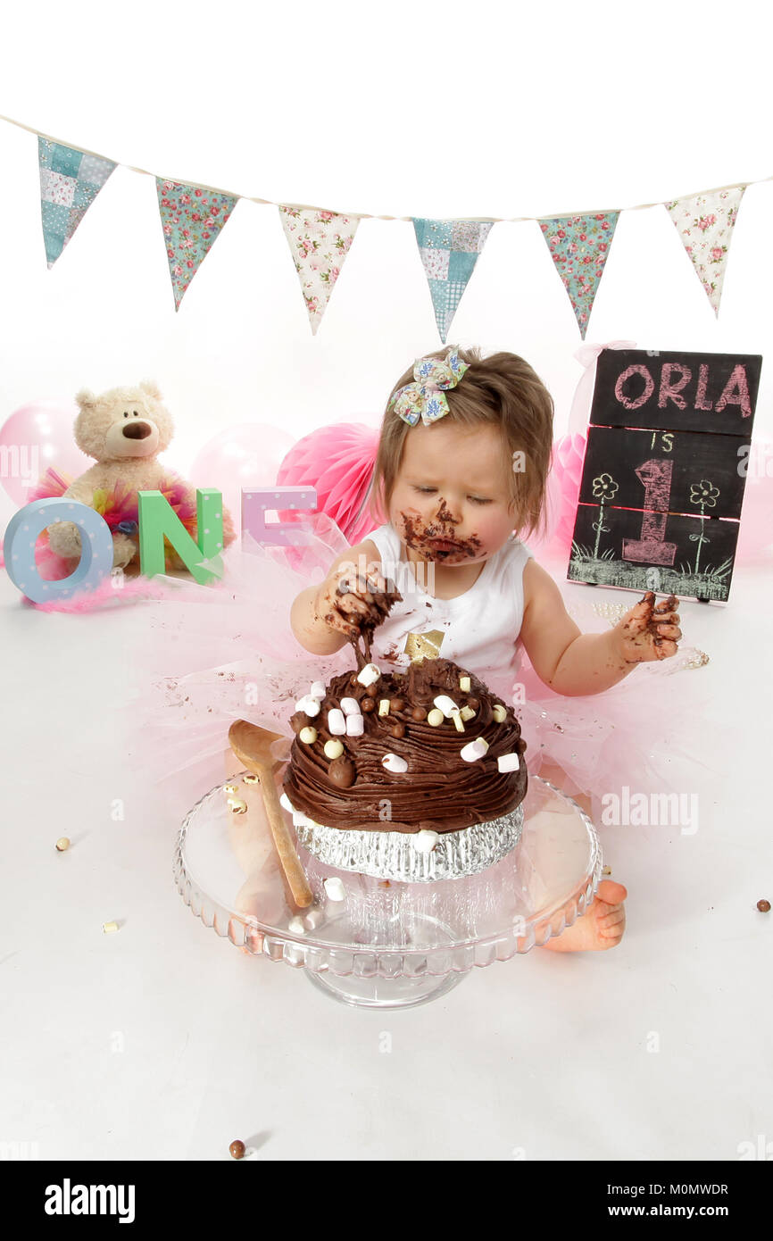 1 year old girl birthday party, cake smash, messy chocolate cake Stock Photo