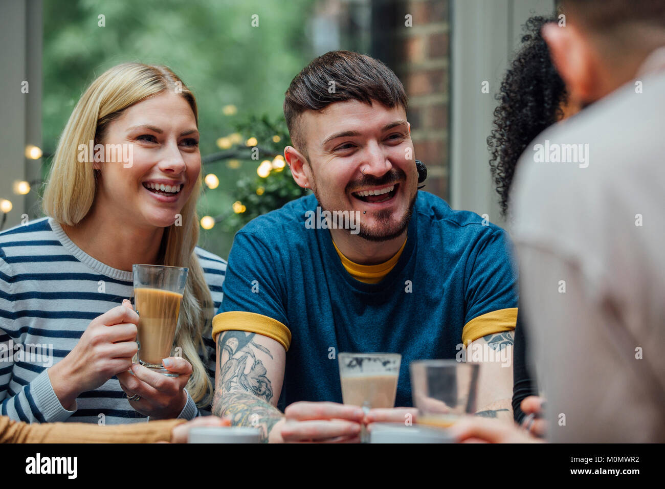 Group of friends are sitting together in a cafe, enjoying coffee and socialising. Stock Photo