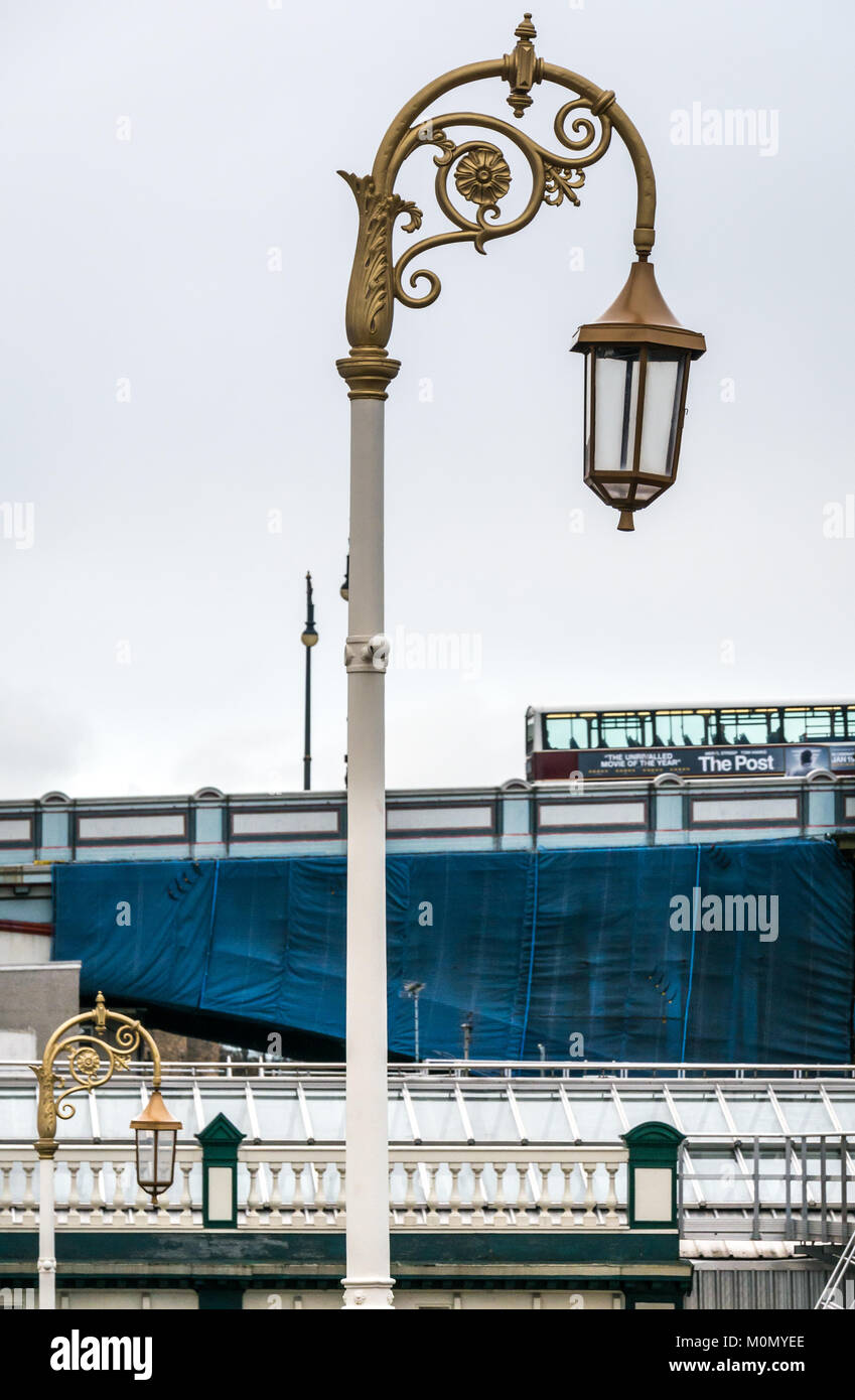 Old fashioned gold ornate Victorian lamp posts, entrance to Waverley station, Edinburgh, Scotland, UK, with Lothian bus on North Bridge in background Stock Photo