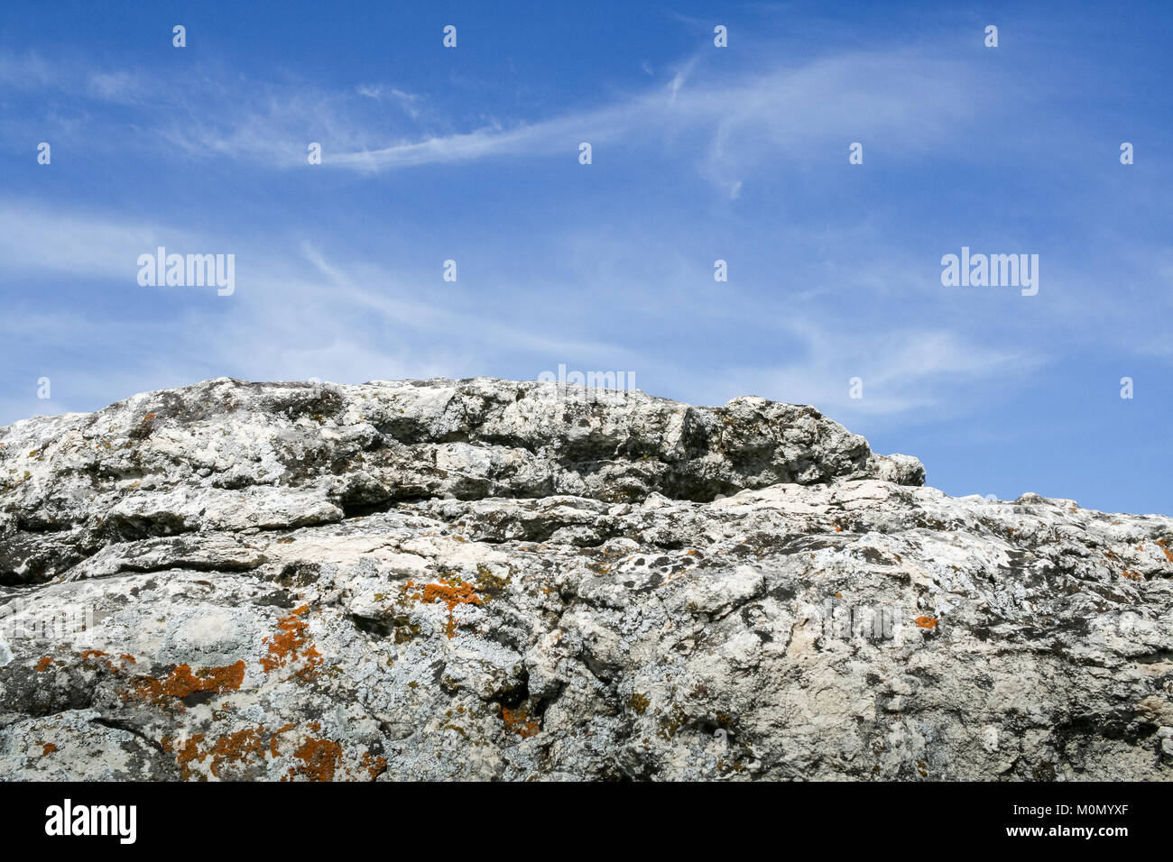 Natural gray layered stone and beautiful blue sky with white layered clouds. Stock Photo