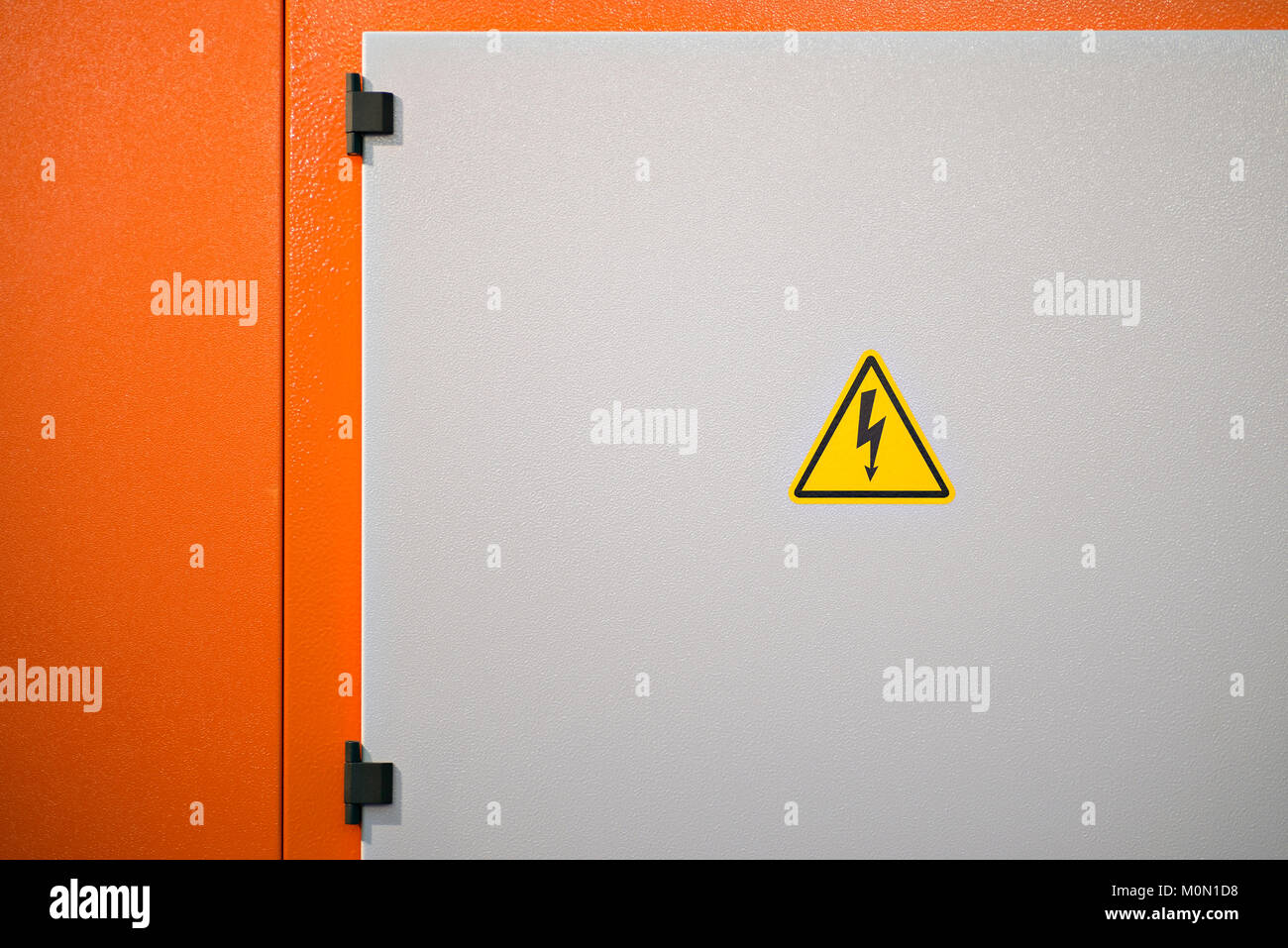 Yellow high voltage electrical hazard sign on a dangerous industrial machine in orange color Stock Photo