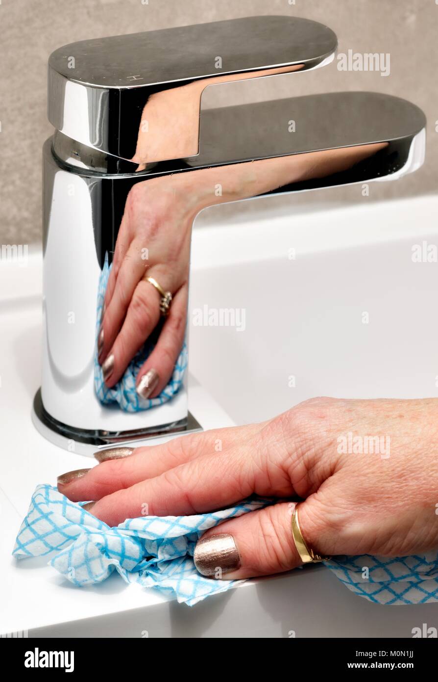 A female hand cleaning a bathroom tap and sink Stock Photo