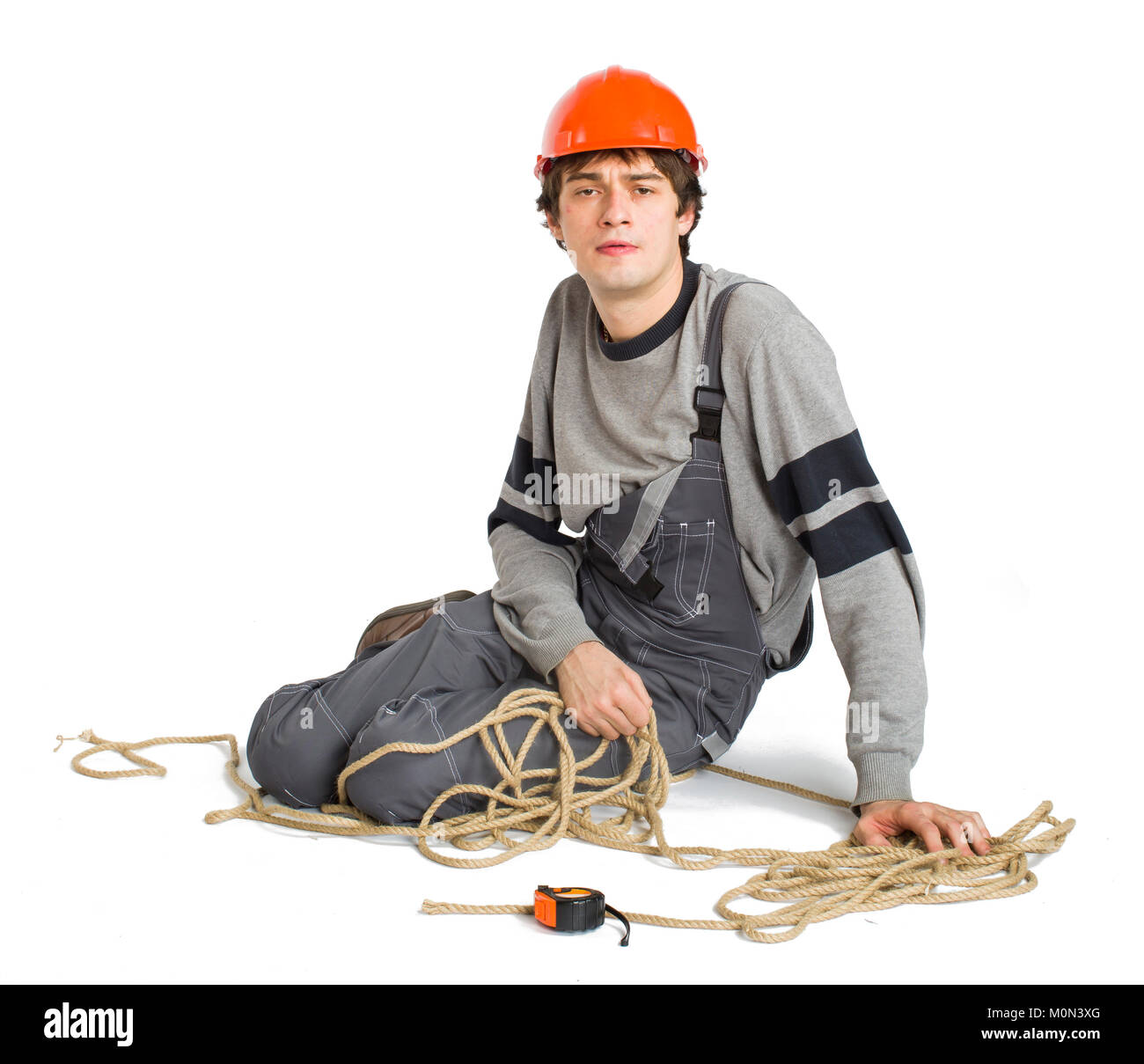 A young worker in grey uniform tied up with rope on white isolated background. Stock Photo