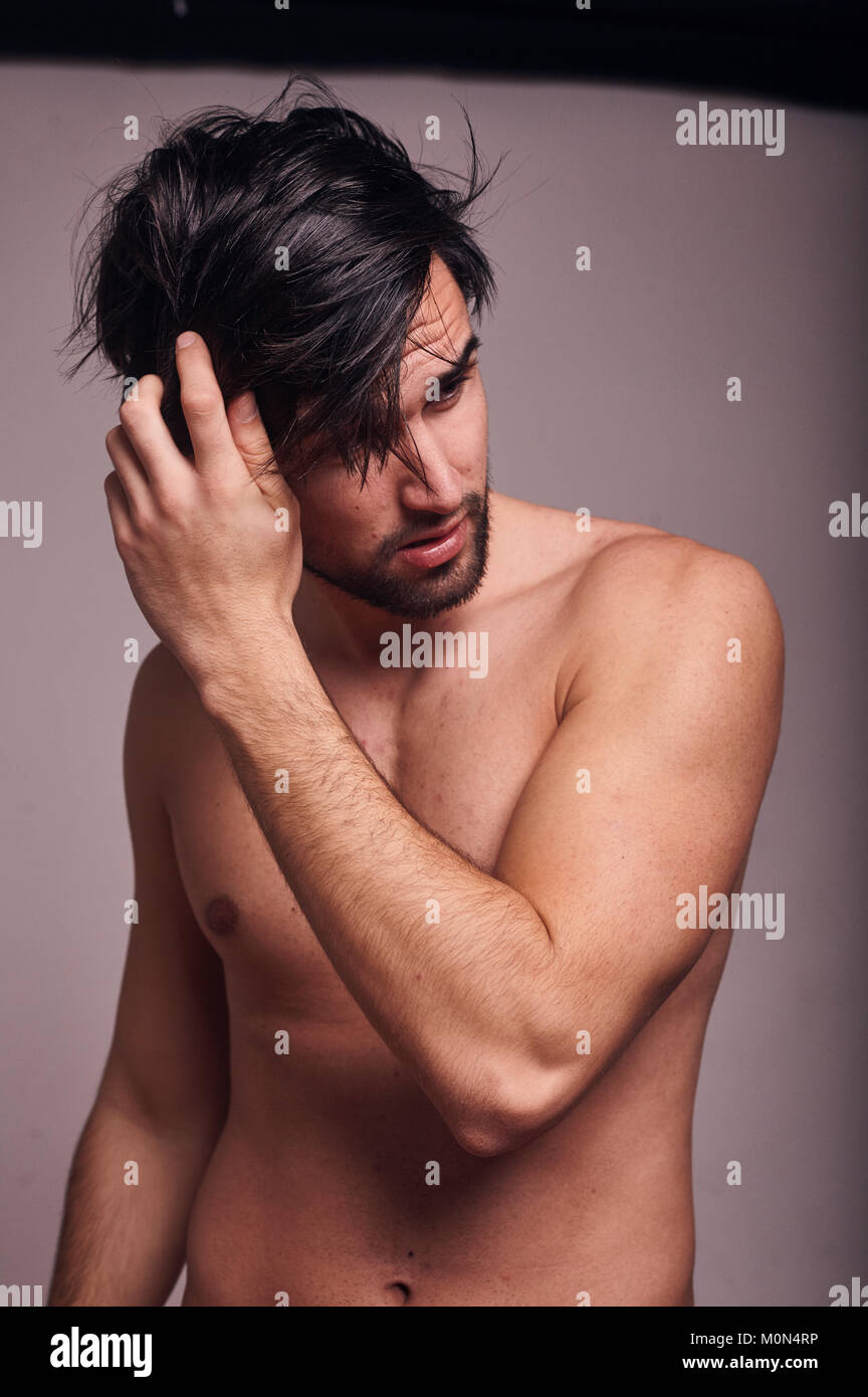 one young man shirtless, messing with his hair, looking away from camera. Stock Photo