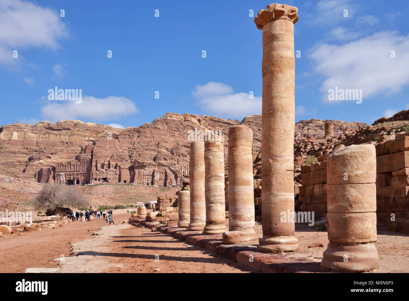 Petra, Jordan - March 15, 2014: Tourists on the Colonnaded street of Petra against ancient Nabataean tombs. Since 1985, Petra is listed as UNESCO Worl Stock Photo