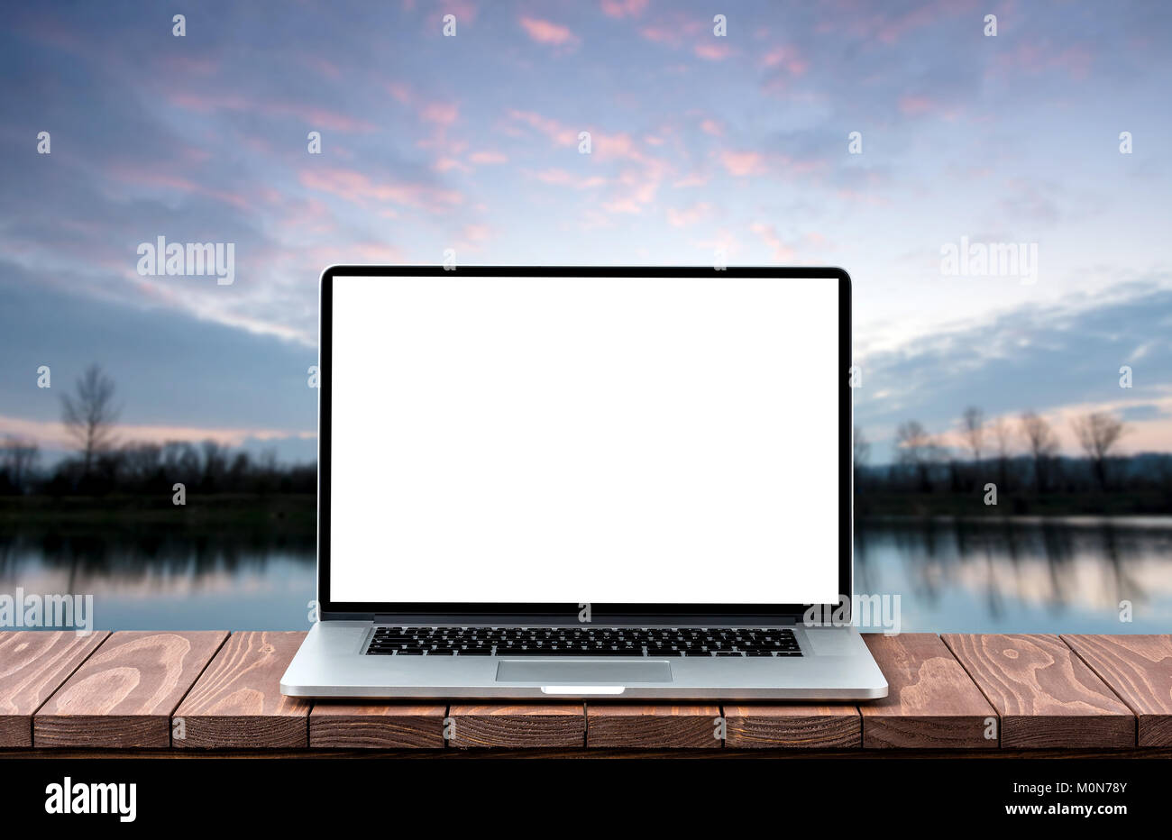 Modern laptop with empty white screen on wooden table against blurred ...