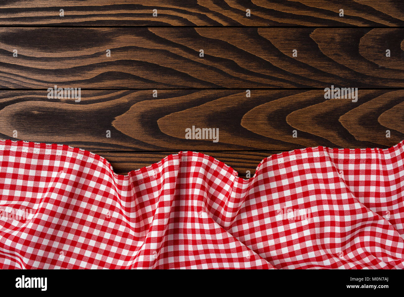 Red checkered tablecloth on an old wooden table. Close up Stock Photo