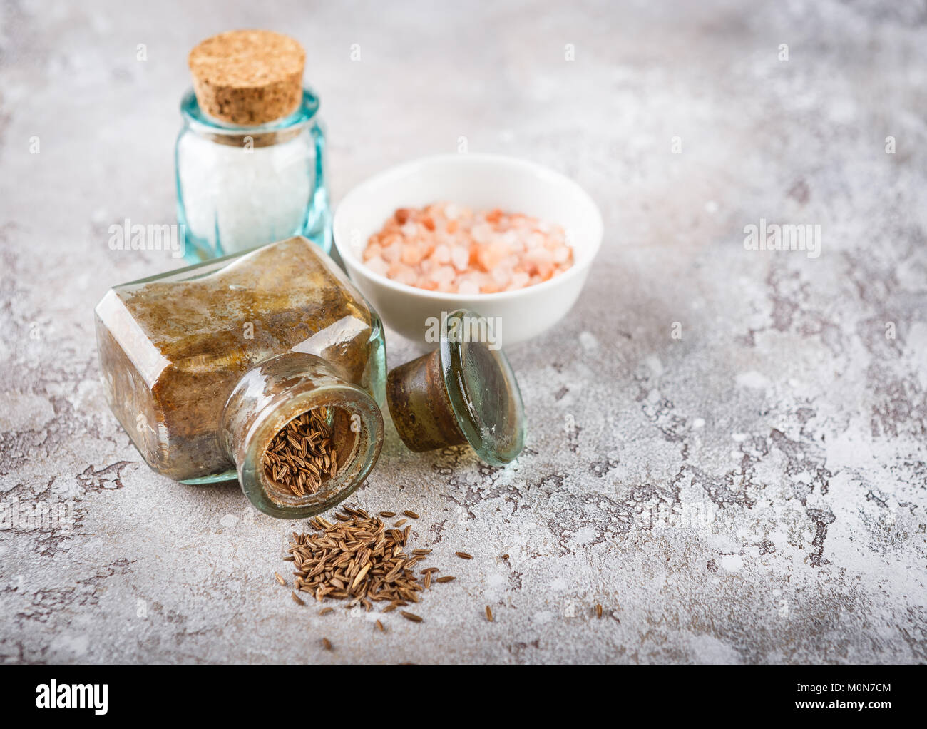 https://c8.alamy.com/comp/M0N7CM/cumin-seeds-in-a-glass-bottle-and-sea-salt-on-a-light-concrete-background-M0N7CM.jpg