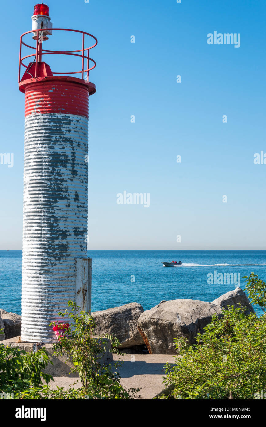 A tall white and red warning beacon light at the waters edge of Lake Ontario in Bluffers Park-Toronto Canada. Stock Photo