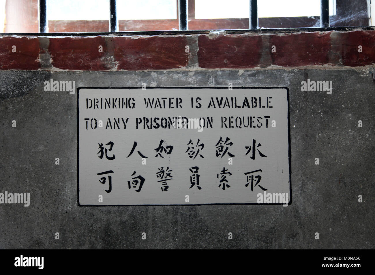 Indication Sign written on the wall in a prison or jail in english and chinese Stock Photo