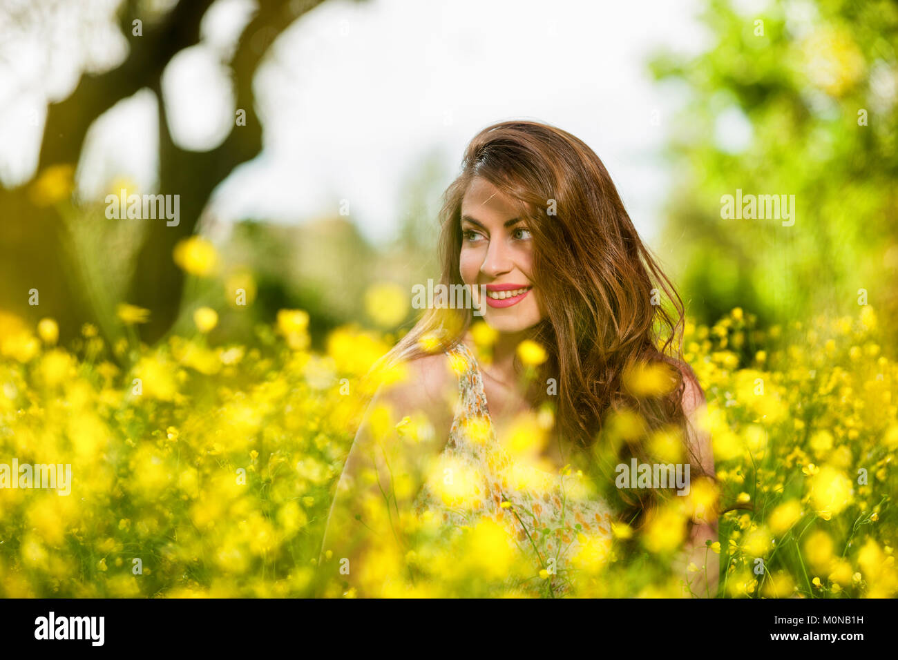 portrait of a beautiful young girl among yellow flowers in the nature ...