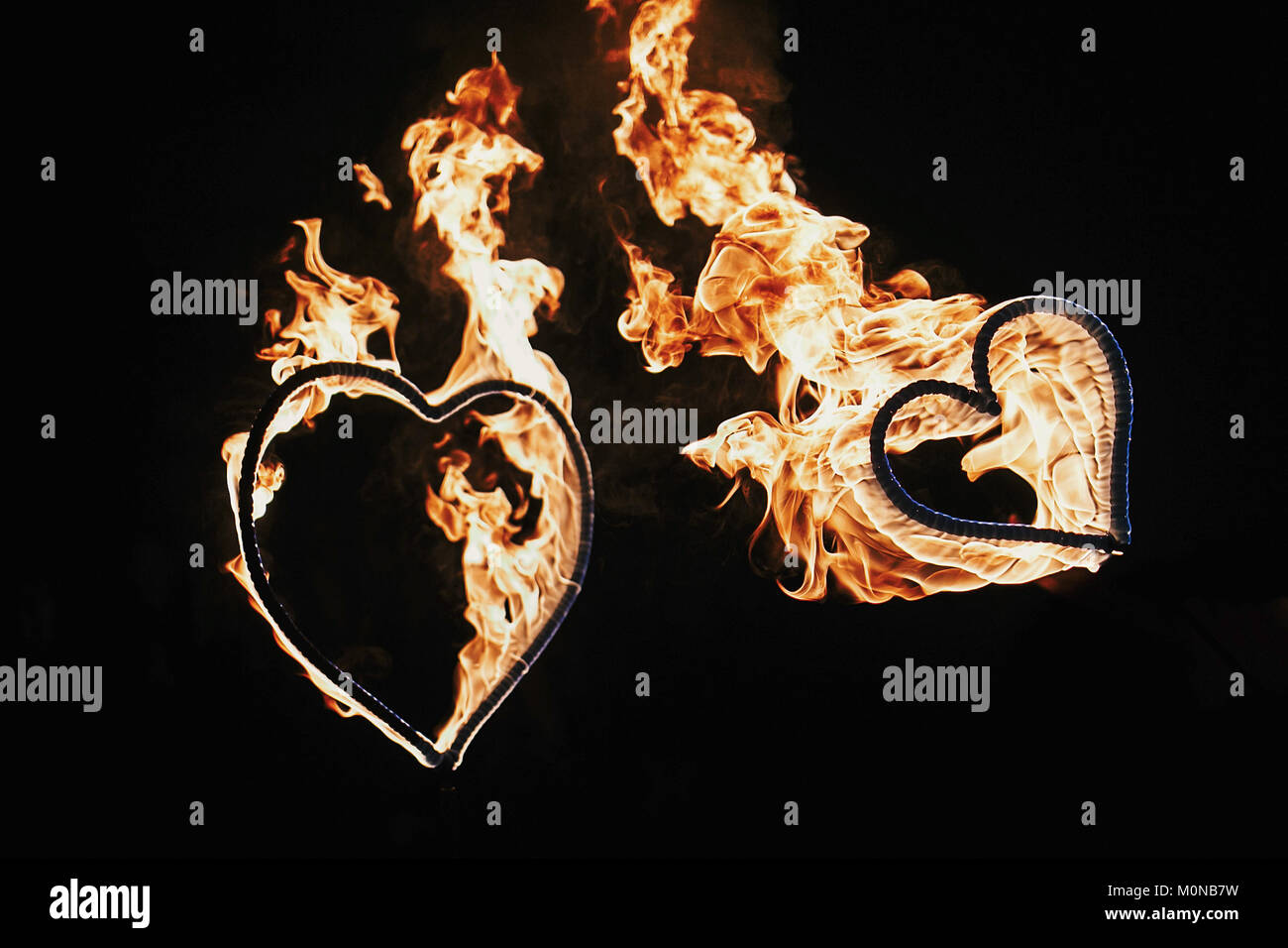 two hearts shaped firework on black background, fire show in night. happy valentine's day card. bengal fire burning heart. space for text. wedding or Stock Photo