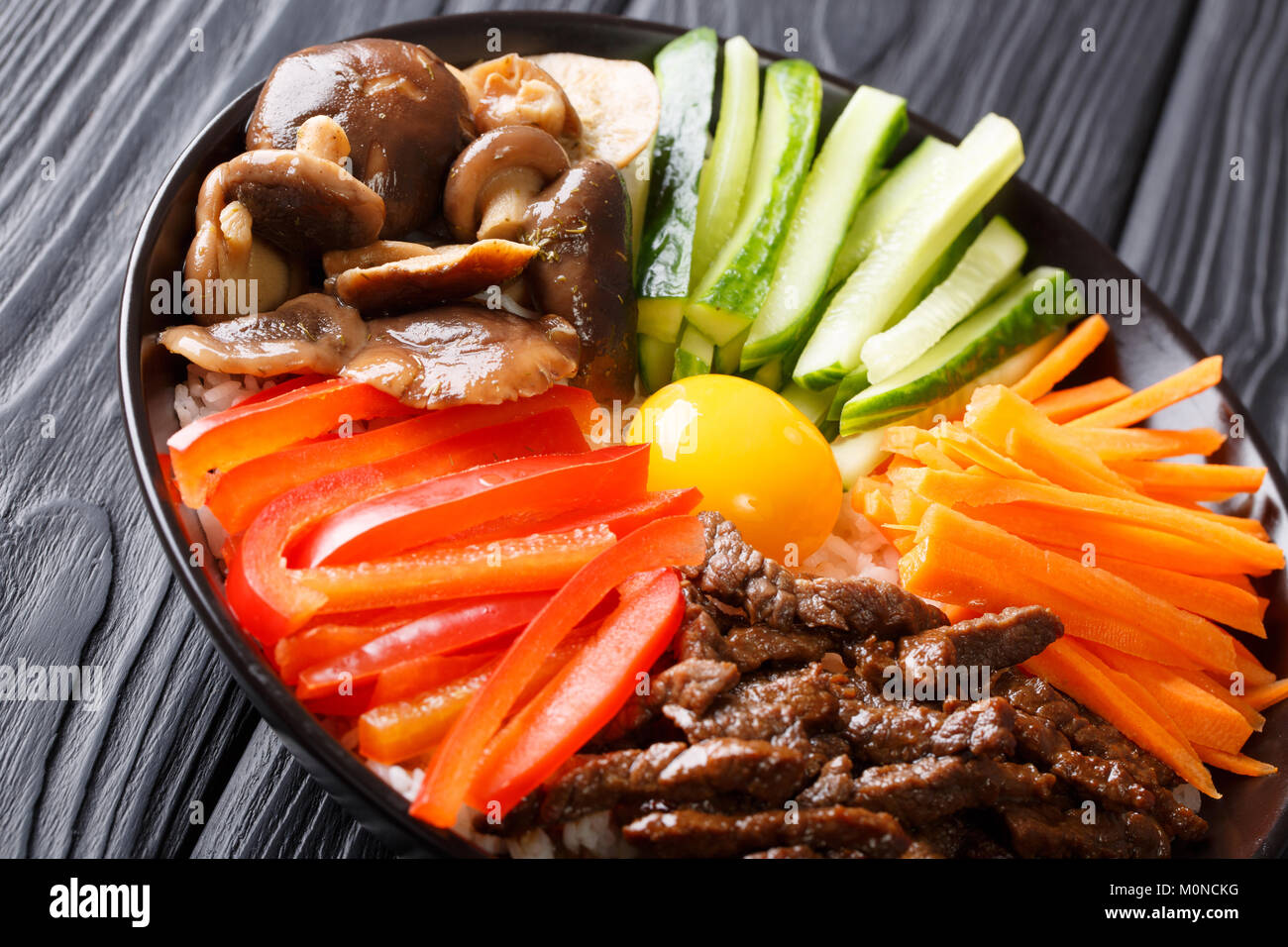 Korean food Bibimbap with fried beef, raw egg, vegetables, shiitake and