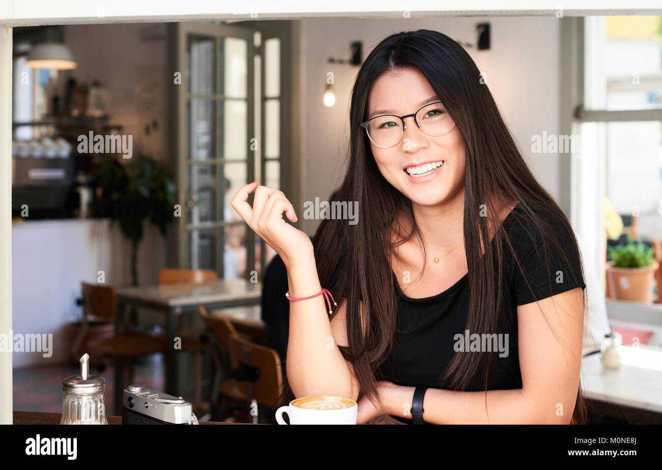 Asian brunette girl smiling at camera in a coffee shop Stock Photo - Alamy