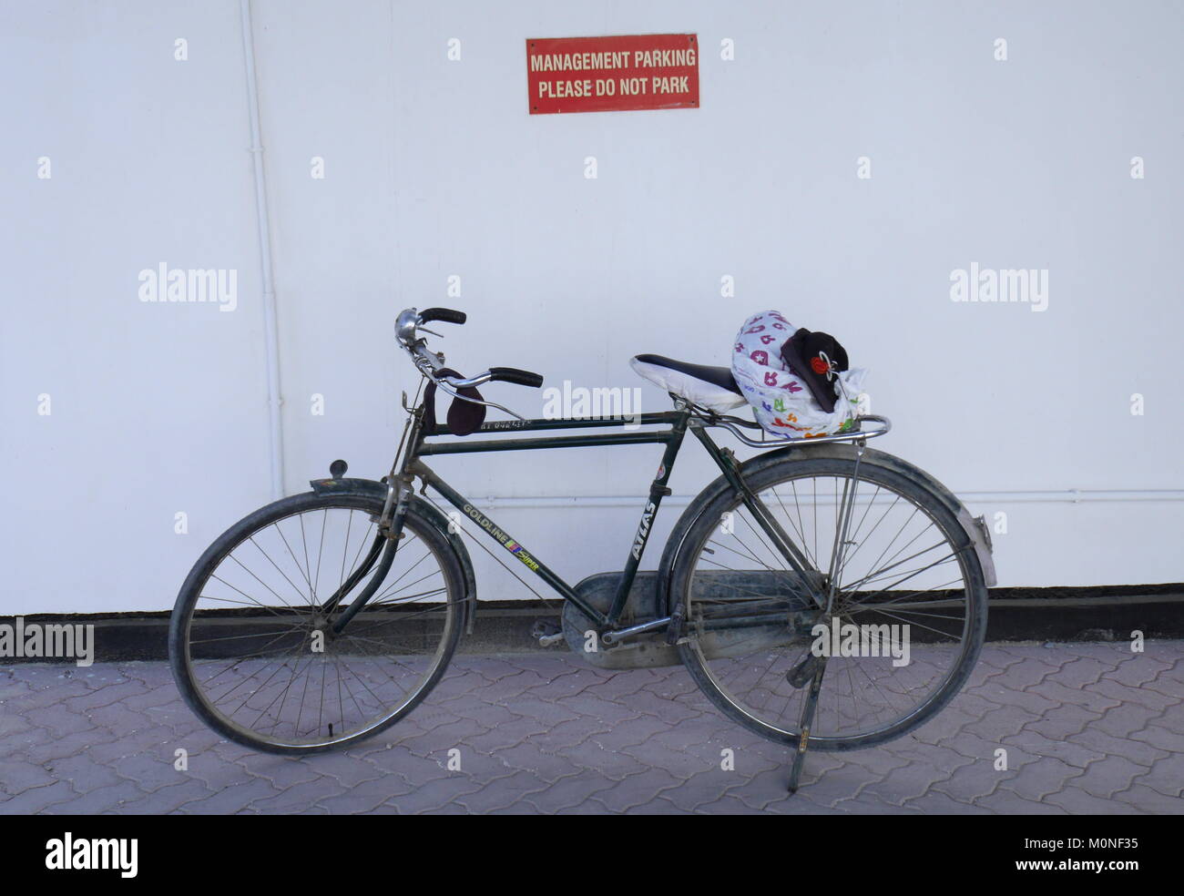 Bicycle parked in front of a management only parking sign, Al Markh, Bahrain Stock Photo