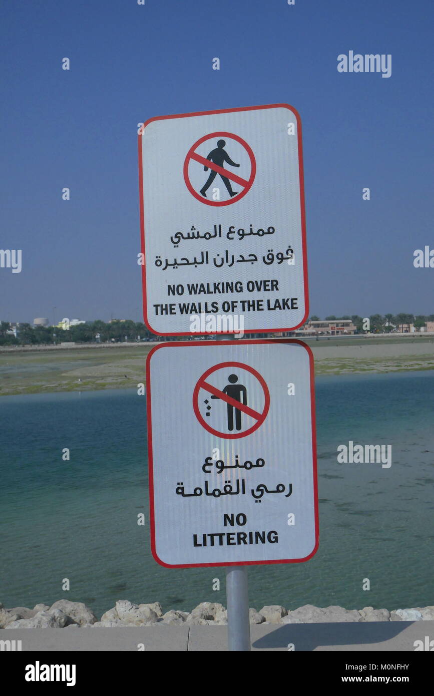 Signs in Arabic and English warning against littering and walking over the walls to the lake, Arad Bay, Kingdom of Bahrain Stock Photo