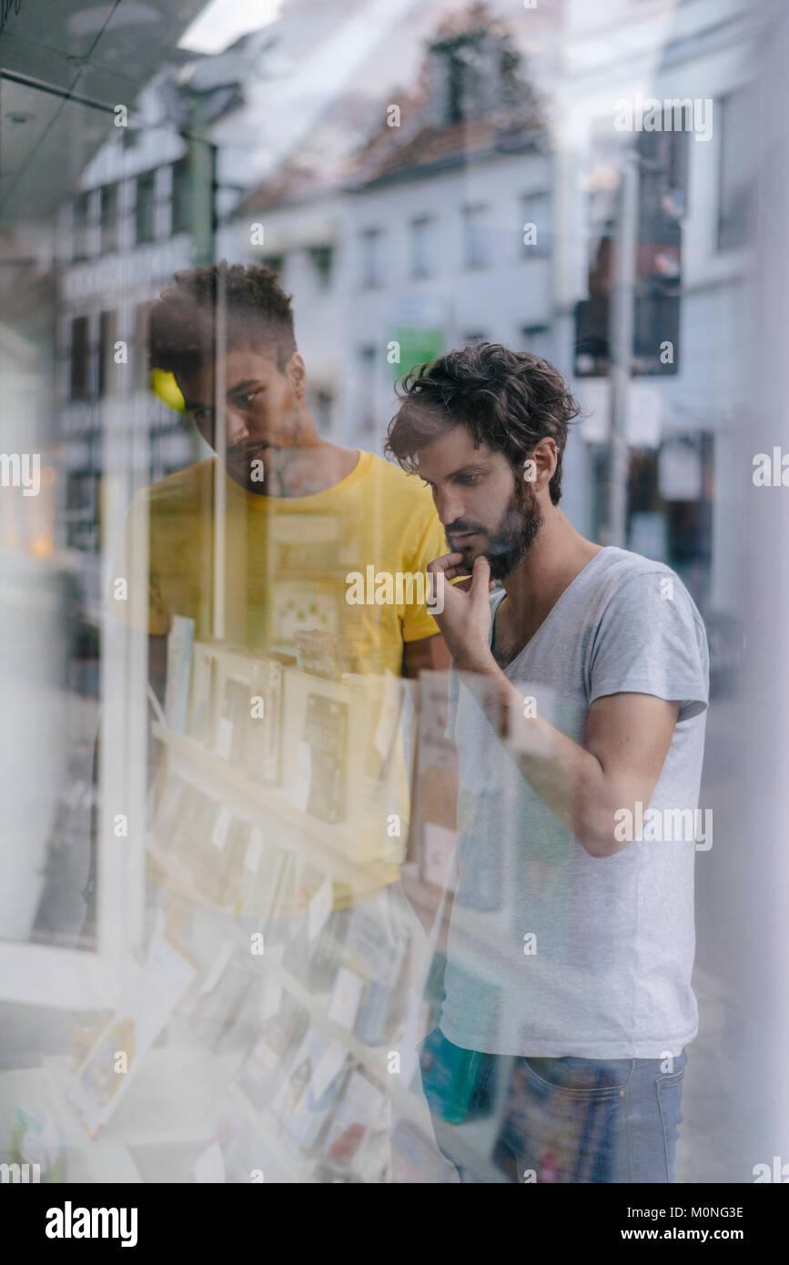 Two friends in the city looking in shop window of a bookstore Stock Photo