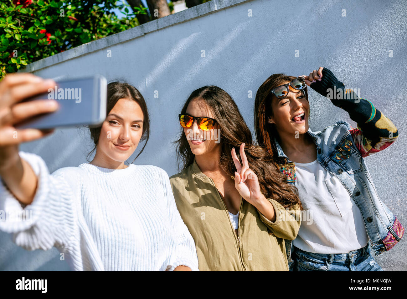 Three smiling young women taking selfie with smartphone Stock Photo - Alamy