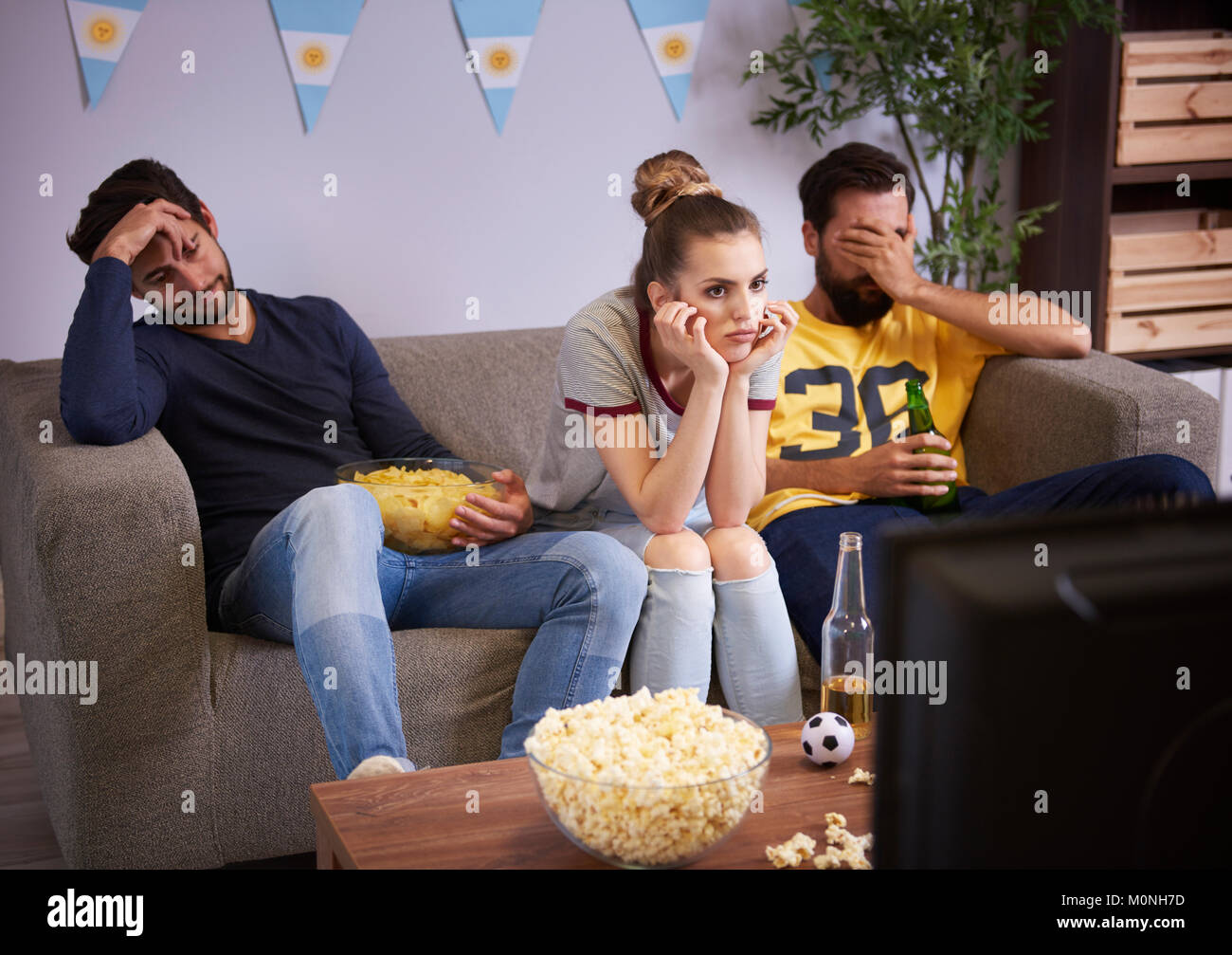 Disappointed friends sitting on the sofa watching Tv Stock Photo