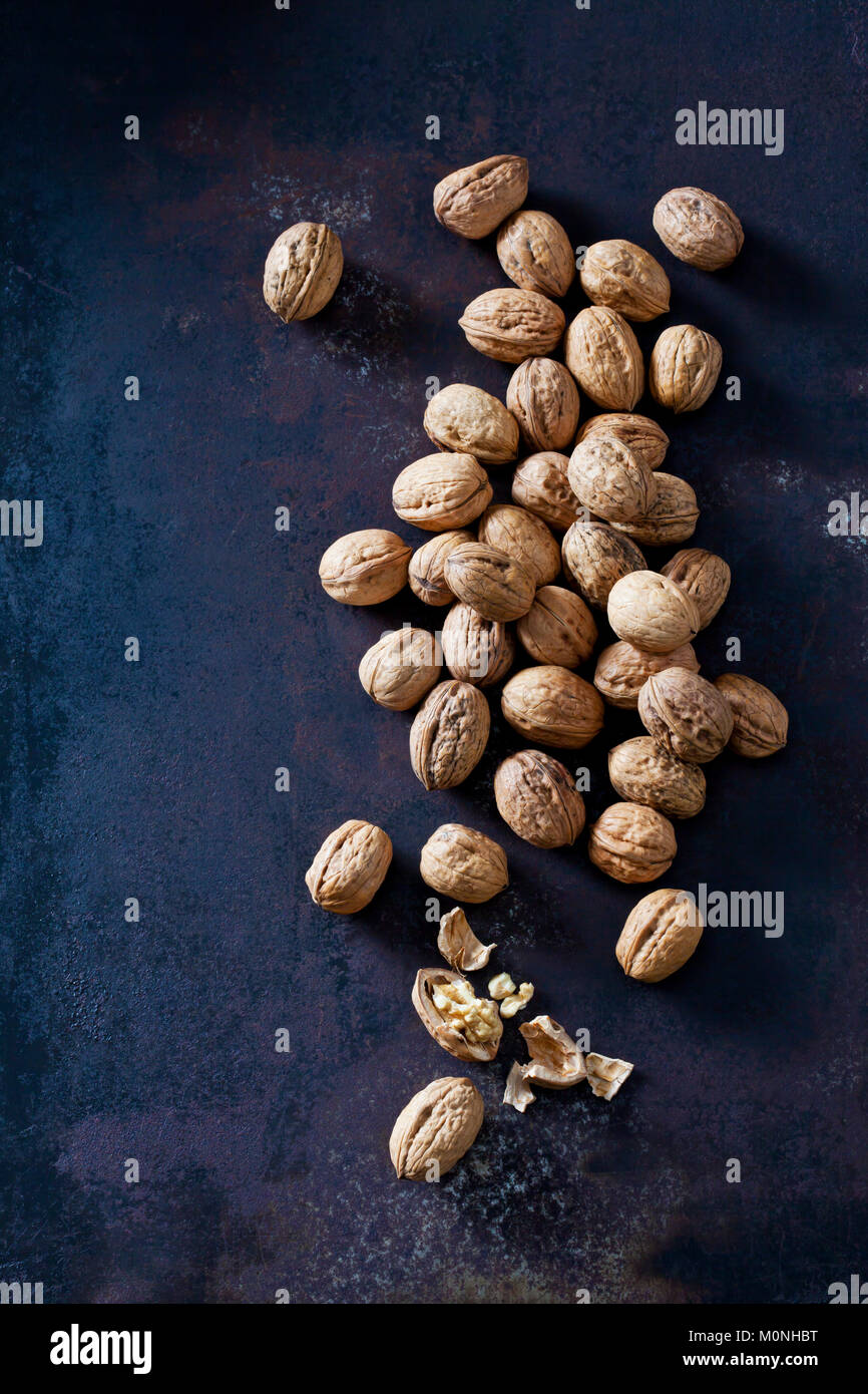 Whole and cracked walnuts on dark metal Stock Photo