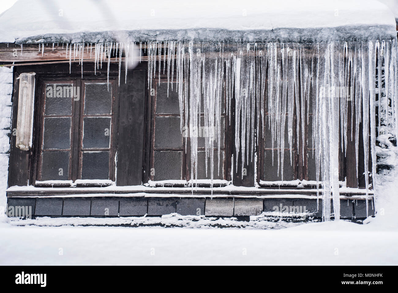 Icicles hanging down from a roof top in winter Stock Photo
