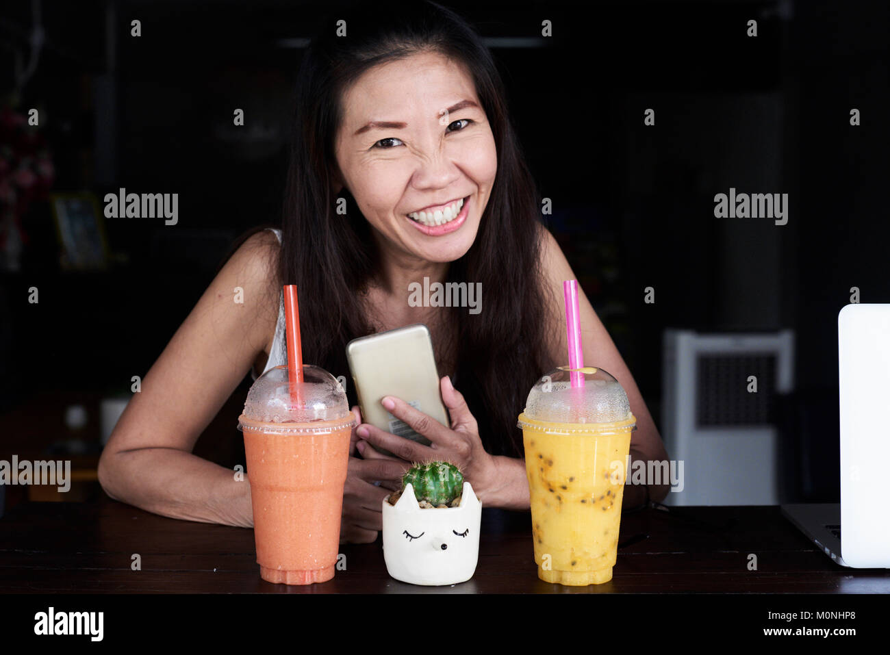 Happy senior brunette business woman having a break at work with two smoothies. Stock Photo