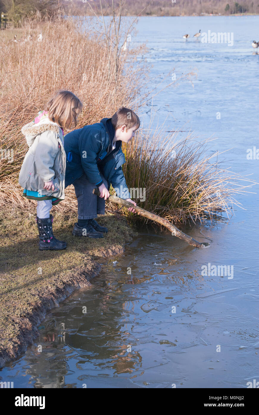 Sheffield, UK- 08 Feb: Children play, smashing the ice on the frozen lake on 08 Feb 2015 at Rother Valley Country Park Stock Photo