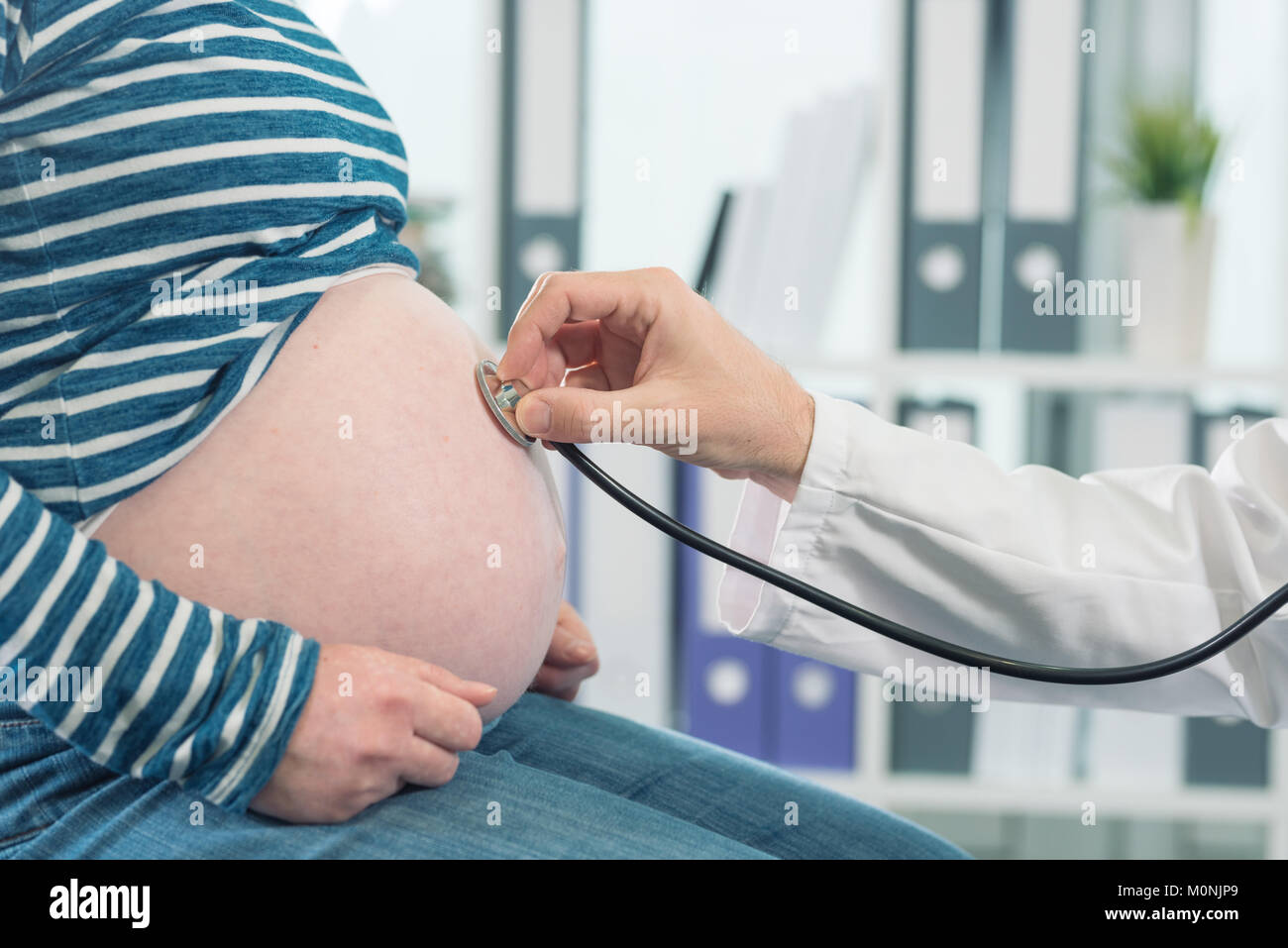 Doctor examining pregnant woman with stethoscope. Health care control during pregnancy. Stock Photo