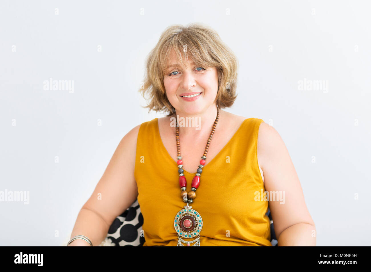 Mature woman sitting on chair in the living room Stock Photo - Alamy