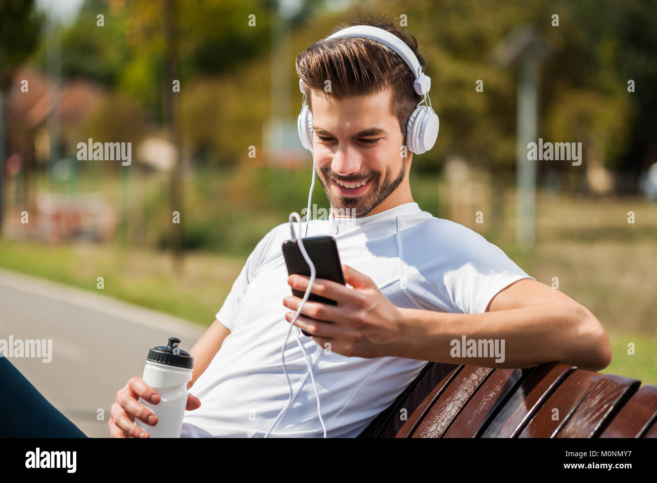 Young man is relaxing after jogging on sunny day. Stock Photo