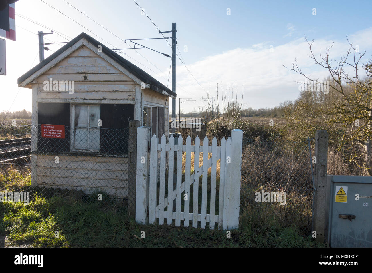 Old railway crossing cabin and wicket gate next to modern railway line Stock Photo