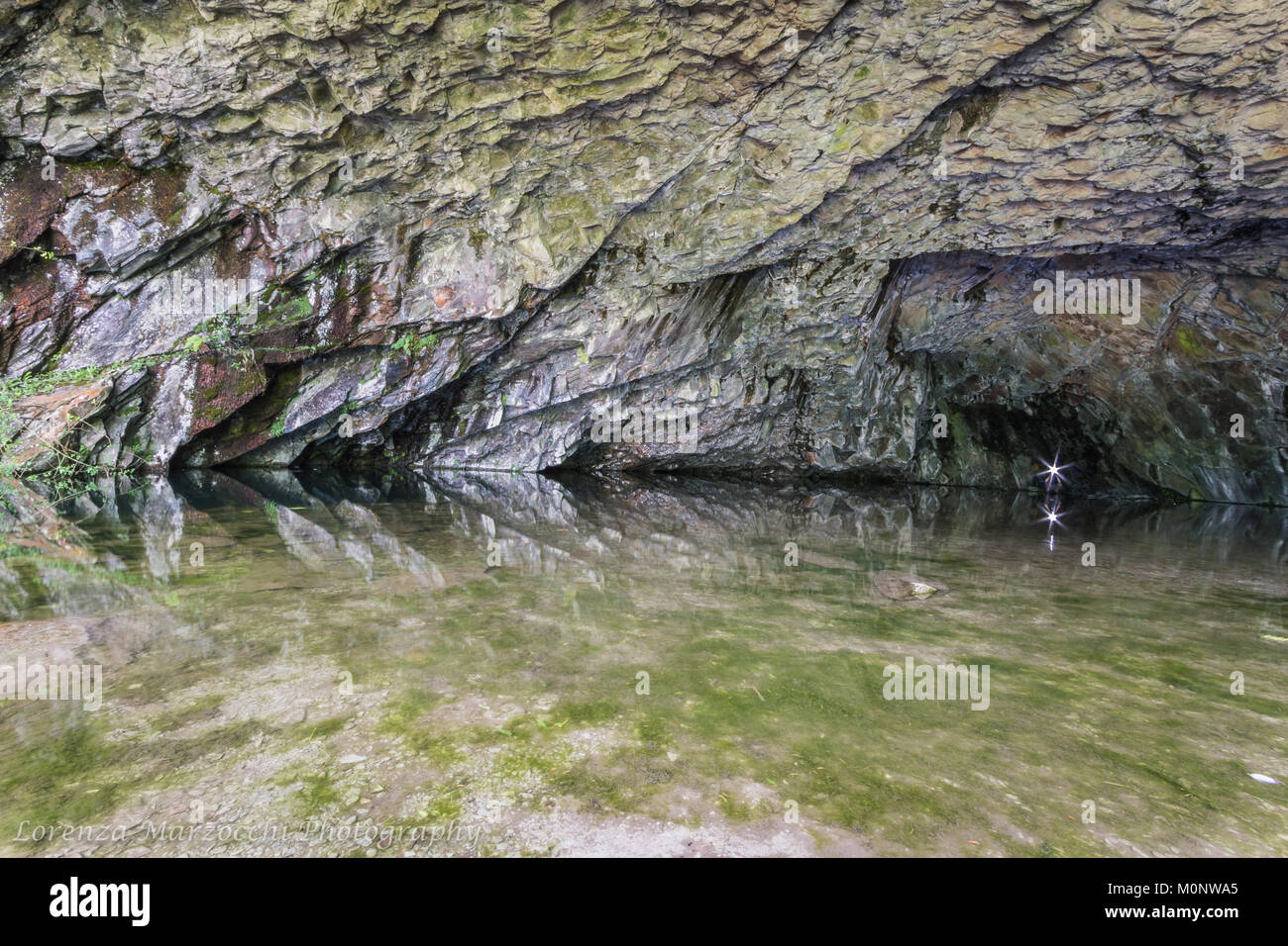 Inside Rydal cave in the Lake District, UK with a reflection of the cave walls in the water. Stock Photo