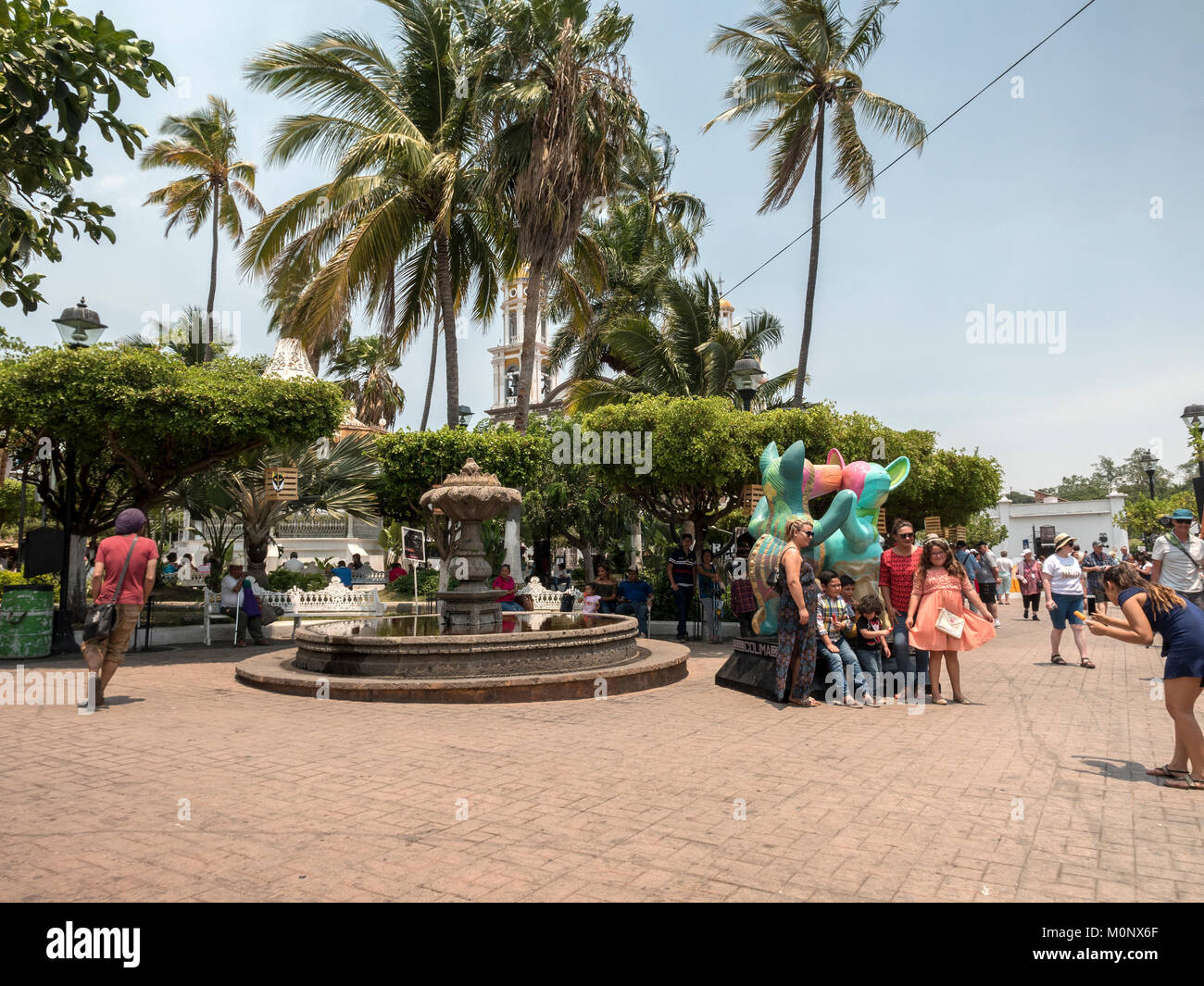 A Family Poses With The Statue Of The Colima Dancing Dogs (Xoloitzcuintle) In The Main Town Square Of Comala Colima Mexico Stock Photo