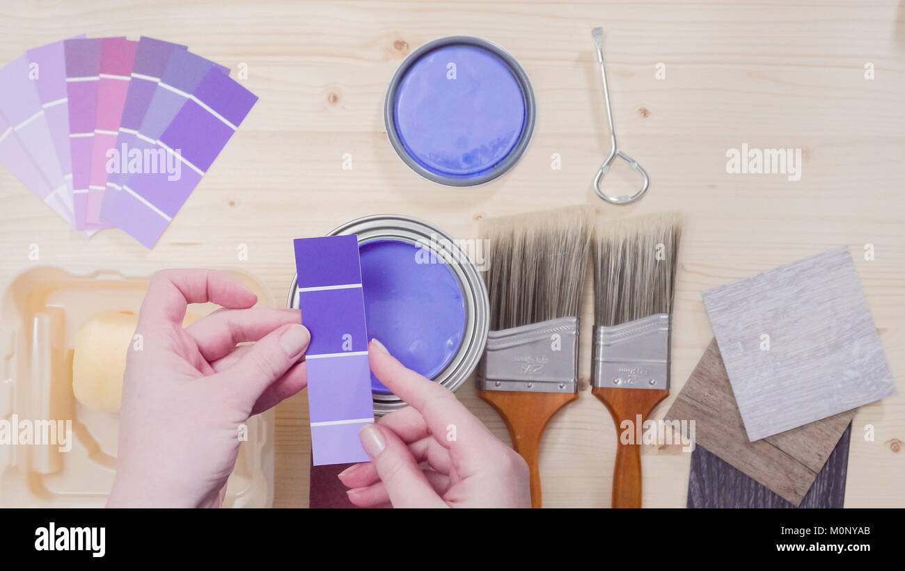 Opened metal paint can with purple paint and other paint tools on