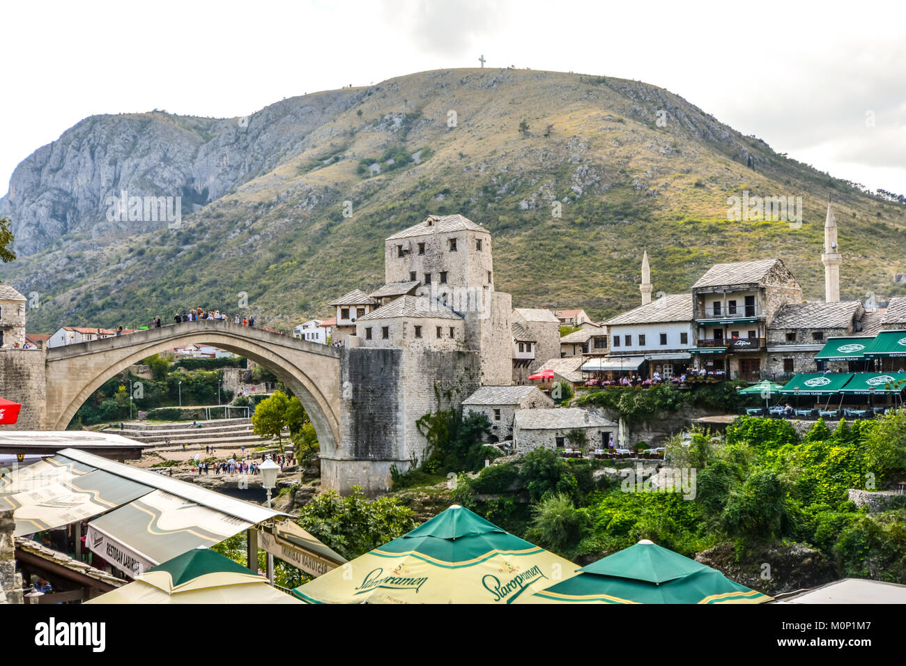 The cross over Mostar on Hum Hill stands atop the mountain overlooking Old Town Mostar, Bosnia Herzegovina with the old bridge below Stock Photo