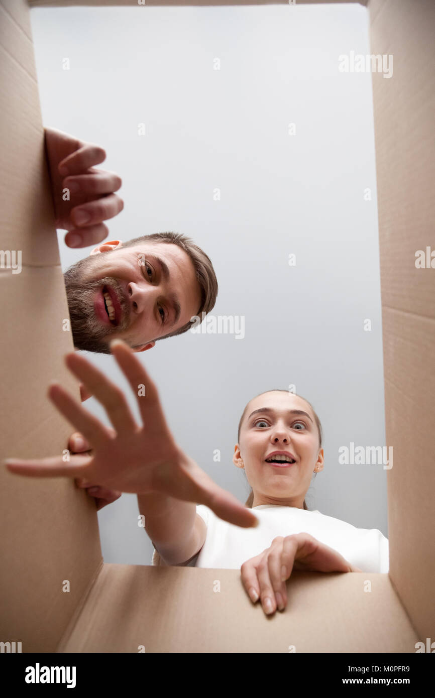 Young surprised impatient couple looking inside open cardboard b Stock Photo