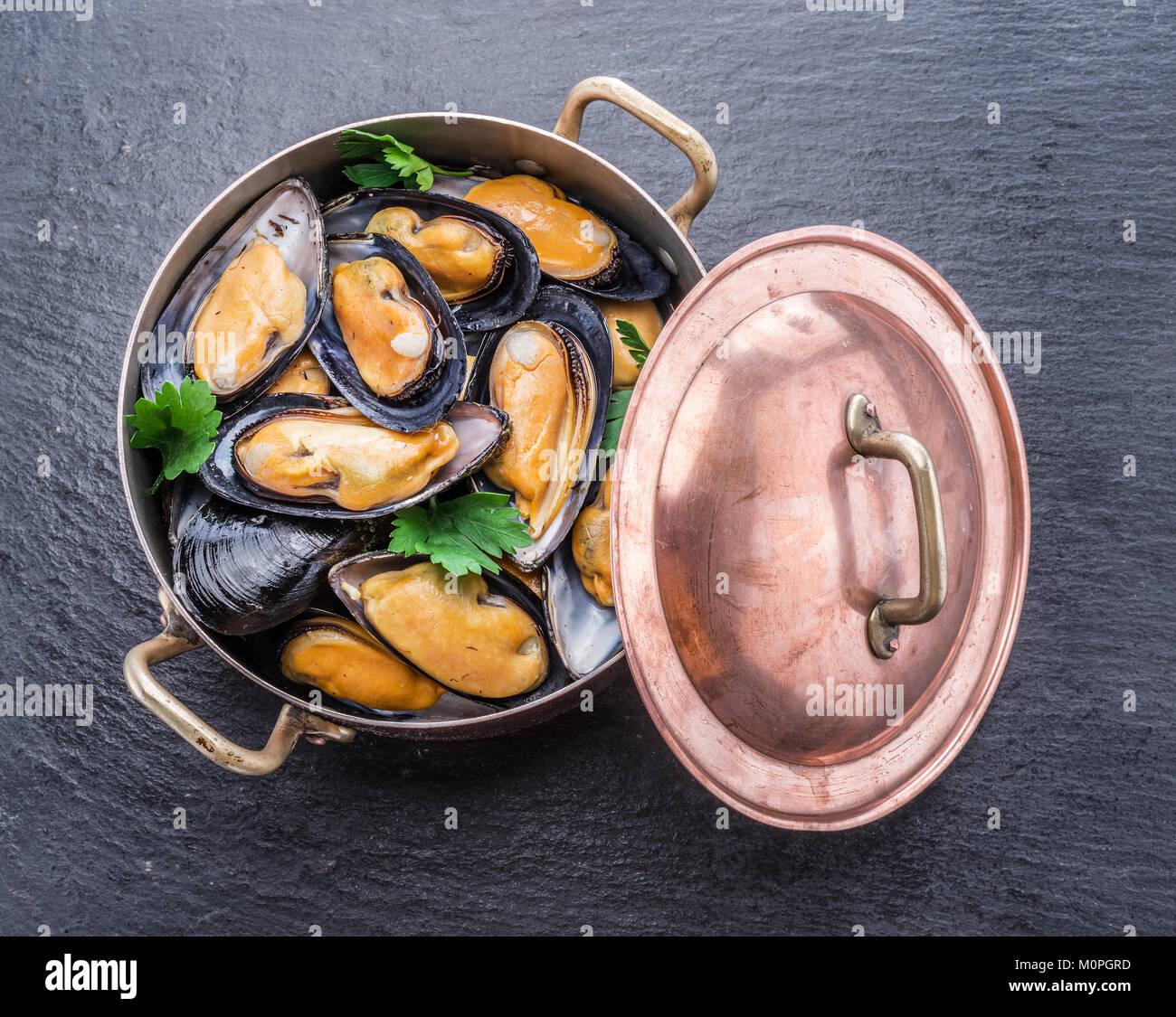 Boiled mussels in copper pan on the graphite background. Stock Photo