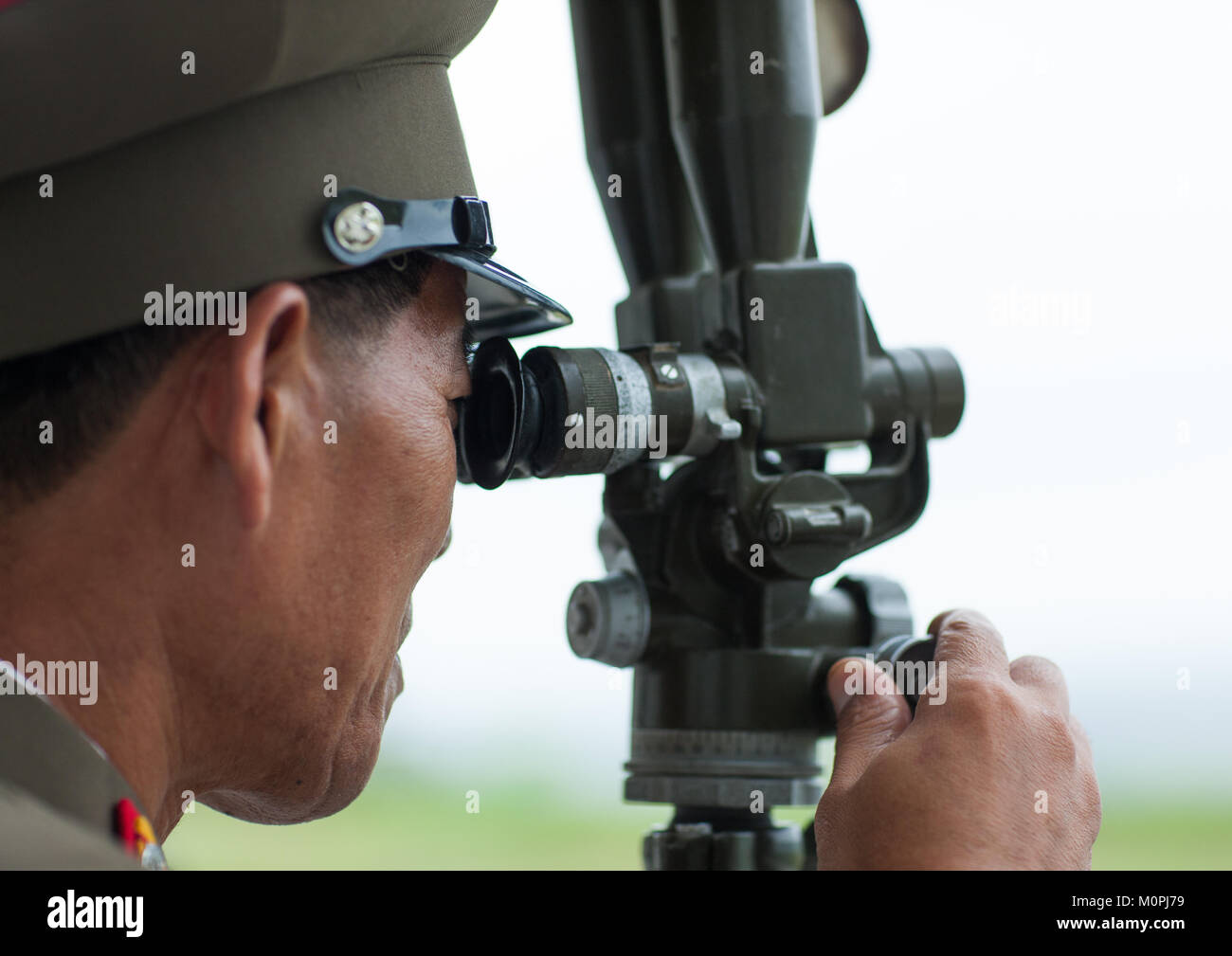 North Korean officer looking south Korea with binoculars at the