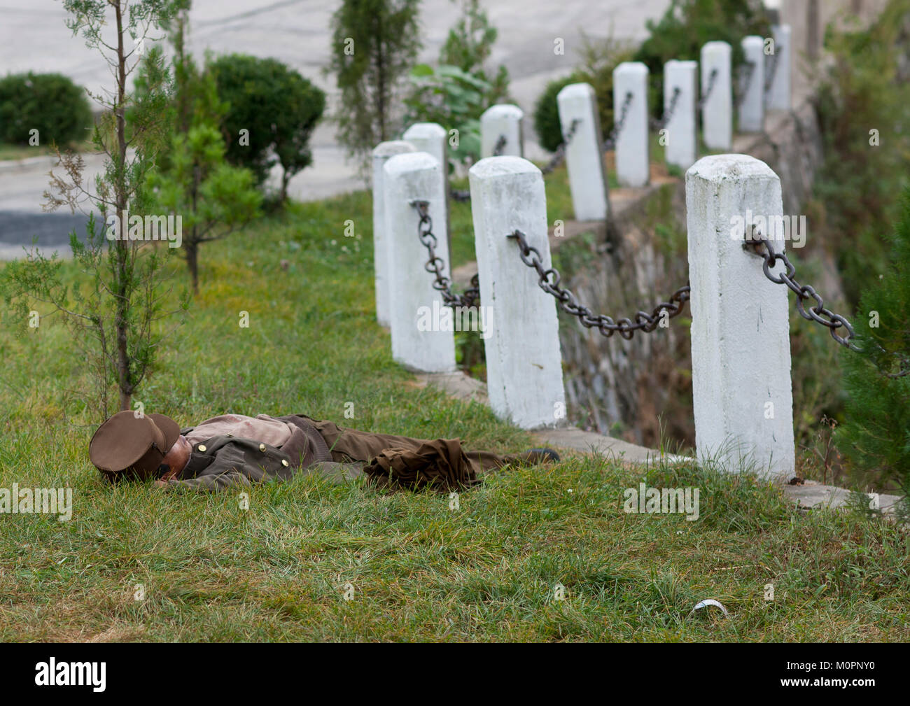 North Korean soldier resting in the grass alongside a country road, Kangwon Province, Wonsan, North Korea Stock Photo