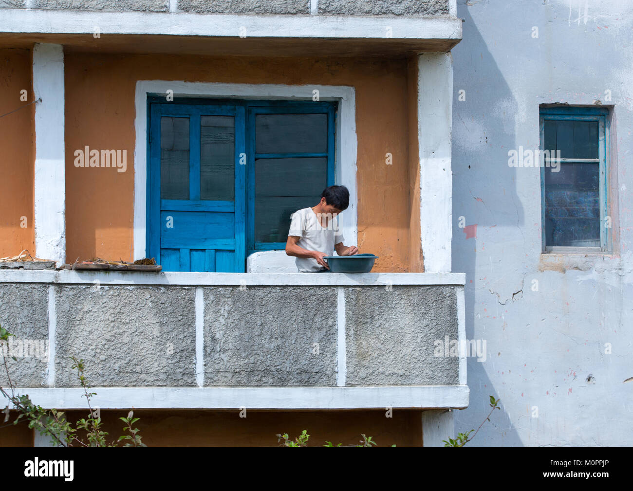 North Korean man washing clothes on his balcony, South Hamgyong