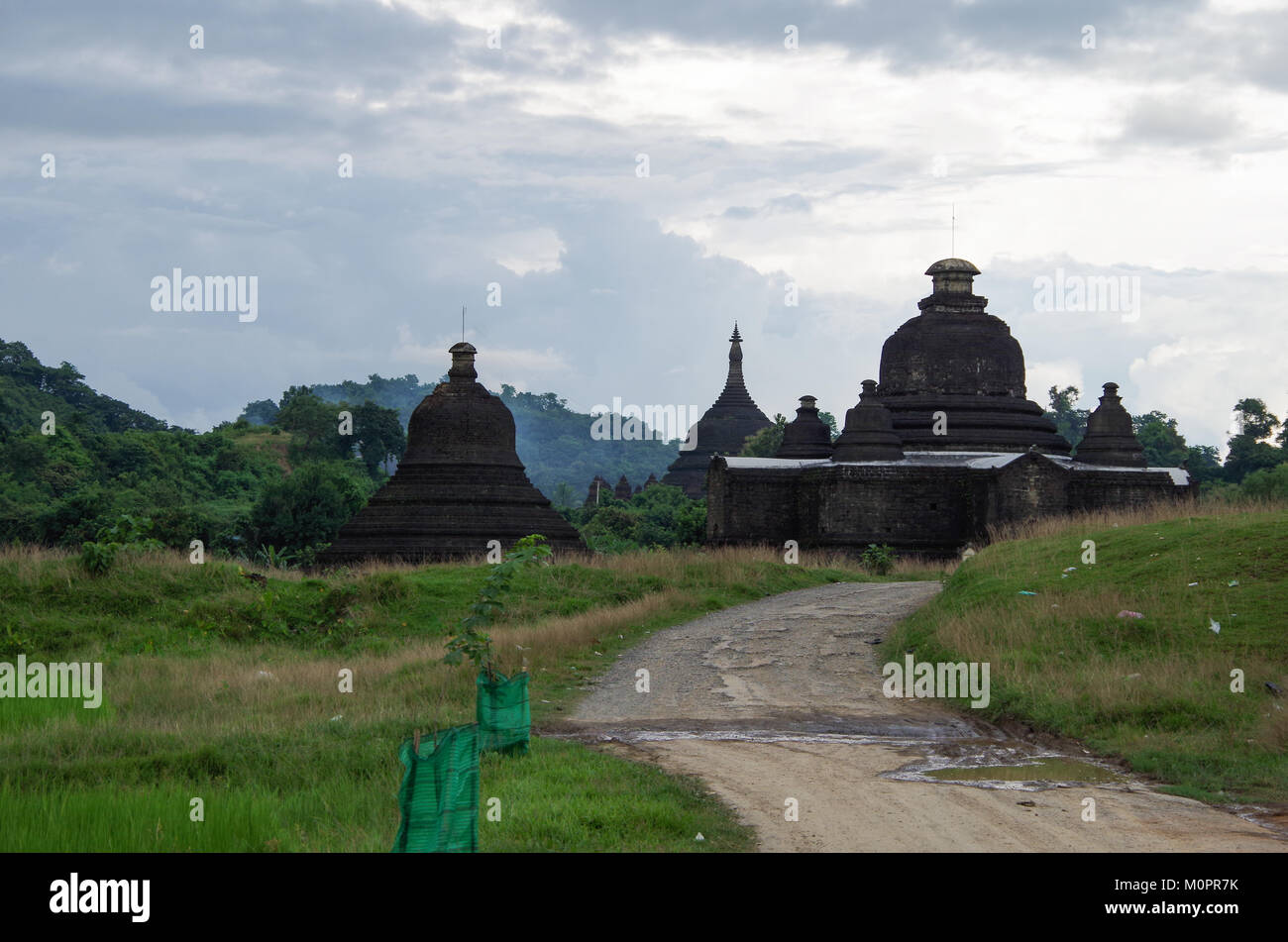 The ancient sites of Mrauk U, Rakhine State, Myanmar and a village road on a cloudy day in green landscape Stock Photo
