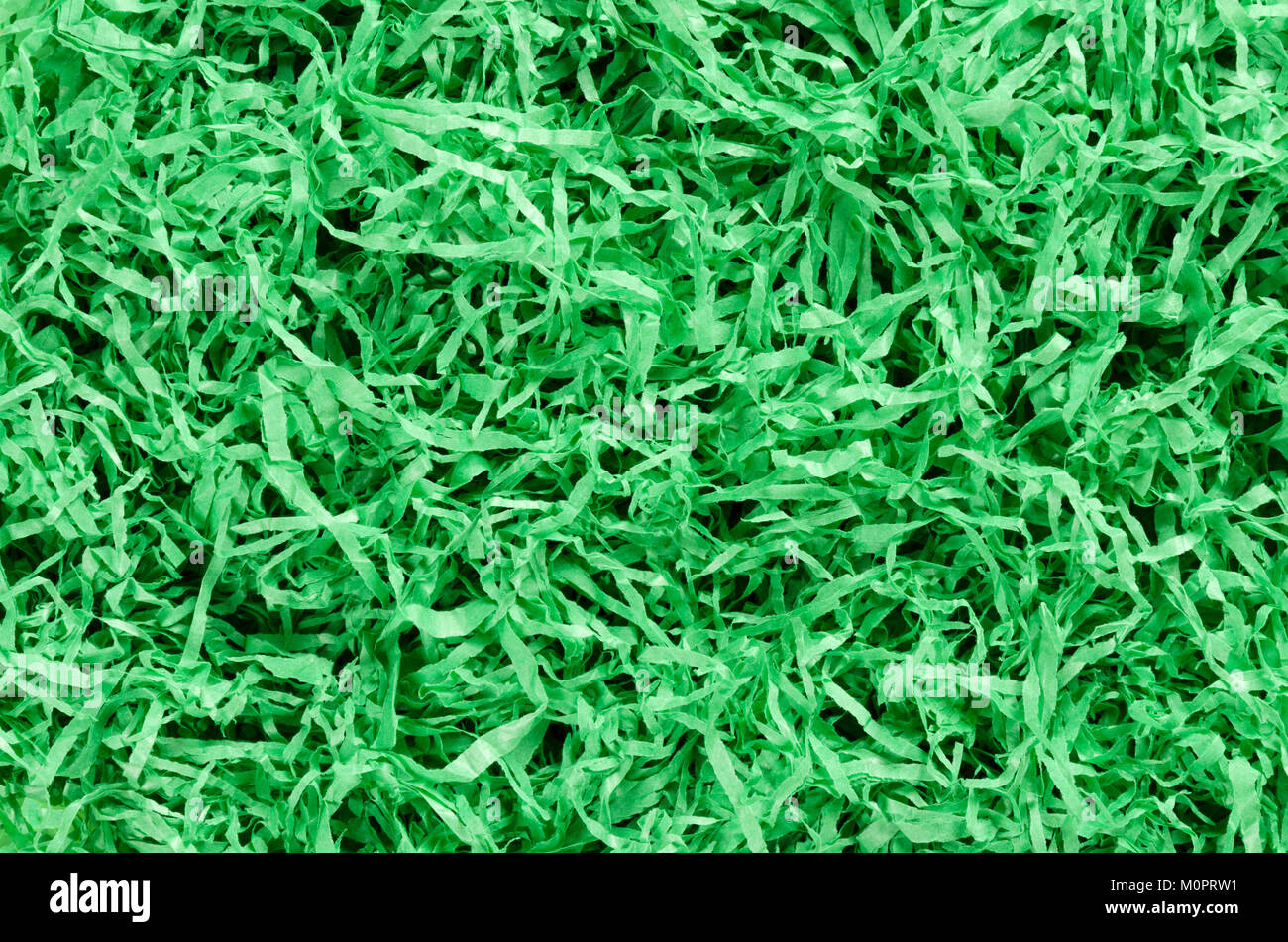 Green paper Easter grass background from above. Colored crinkle grass. Gift basket shred and