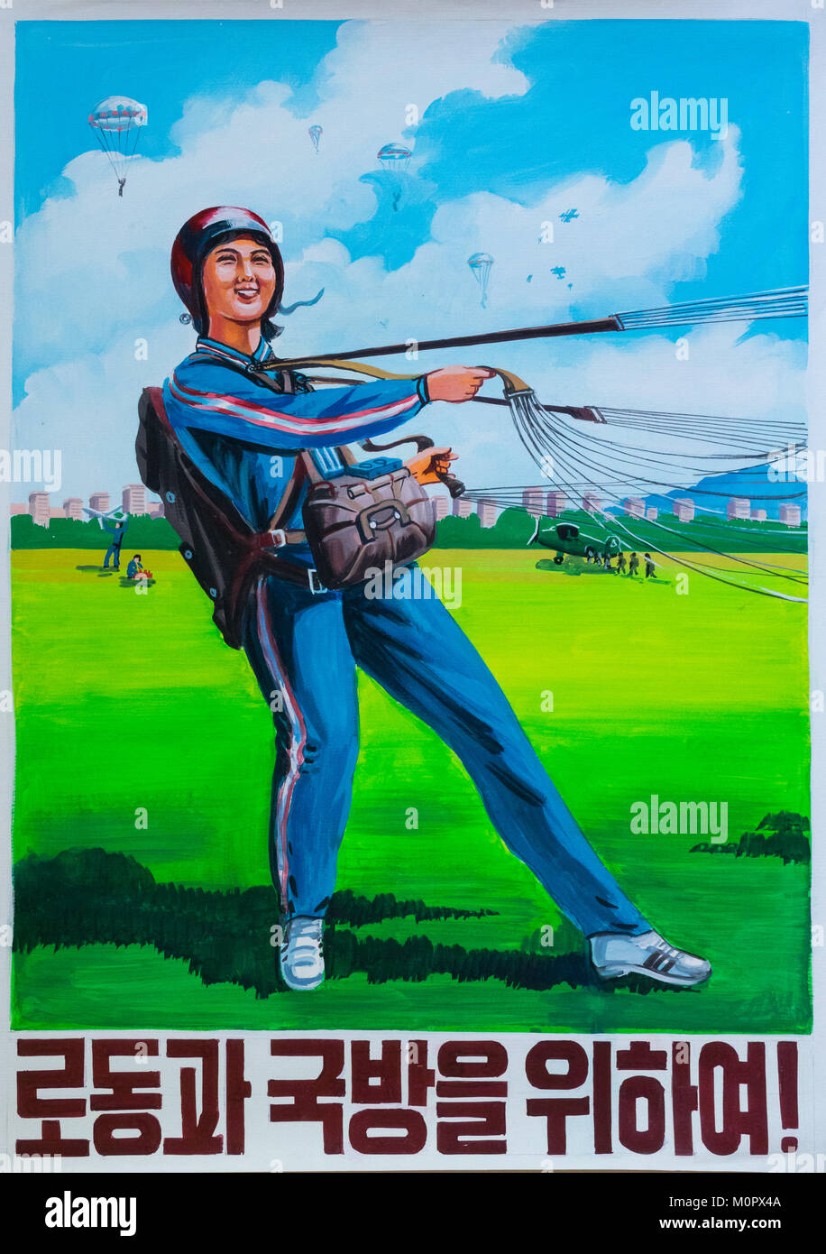 North Korean propaganda poster depicting a female paratrooper witht he slogan for work and national defense!, Pyongan Province, Pyongyang, North Korea Stock Photo