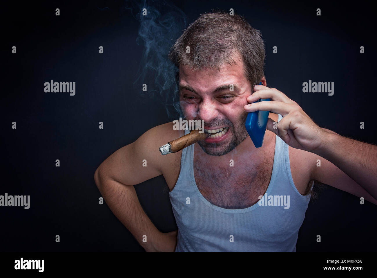 Rude smoking man yelling at his cell phone Stock Photo