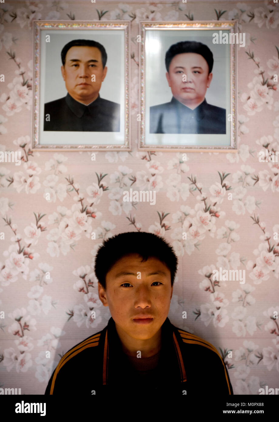 North Korean boy posing below the portraits of the Dear Leaders in his home, Kangwon Province, Chonsam Cooperative Farm, North Korea Stock Photo