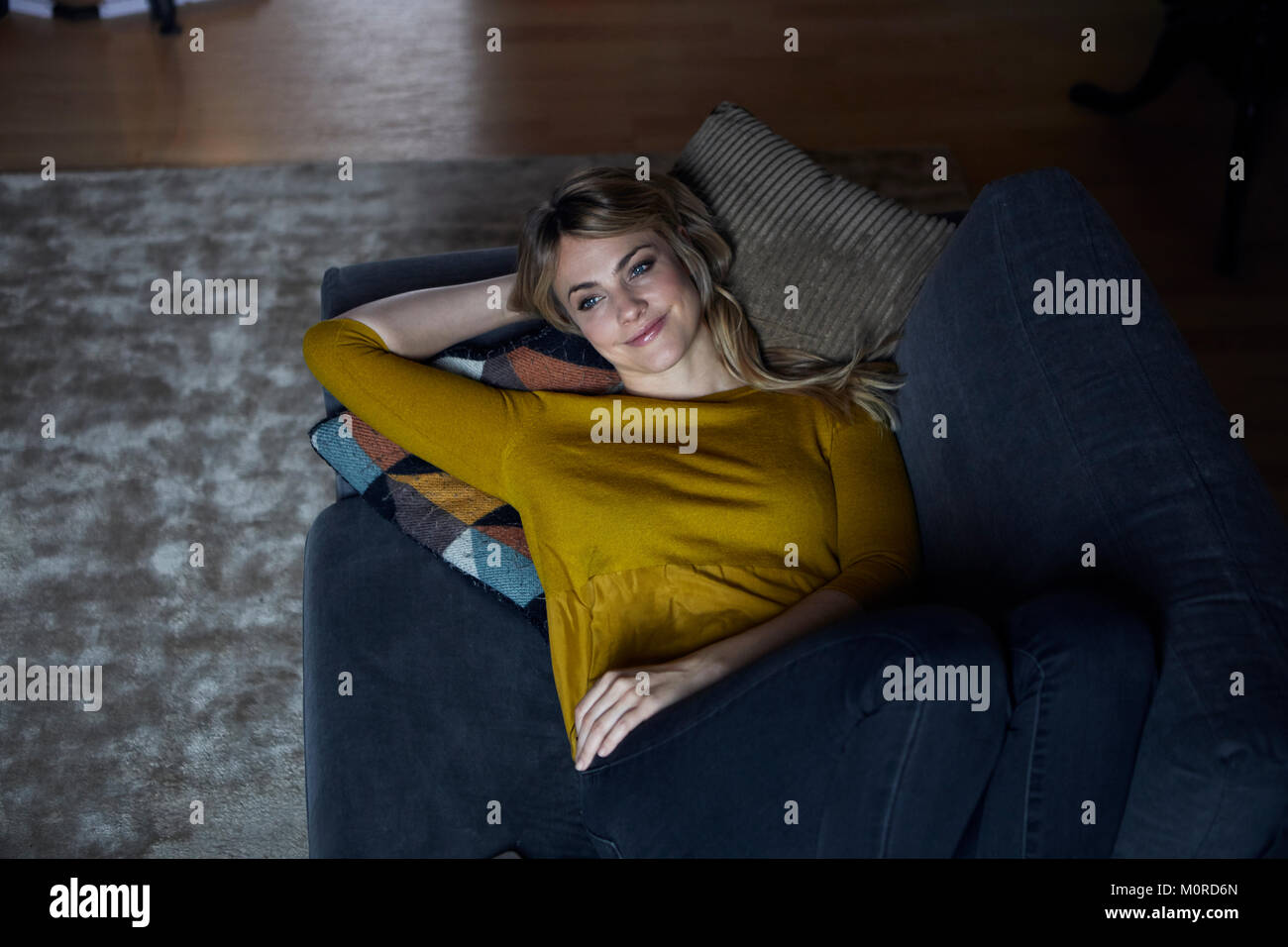 Portrait of smiling woman relaxing on couch at home Stock Photo - Alamy