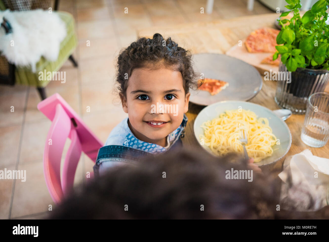 Portrait of a cheeky little girl eating spaghetti Stock Photo