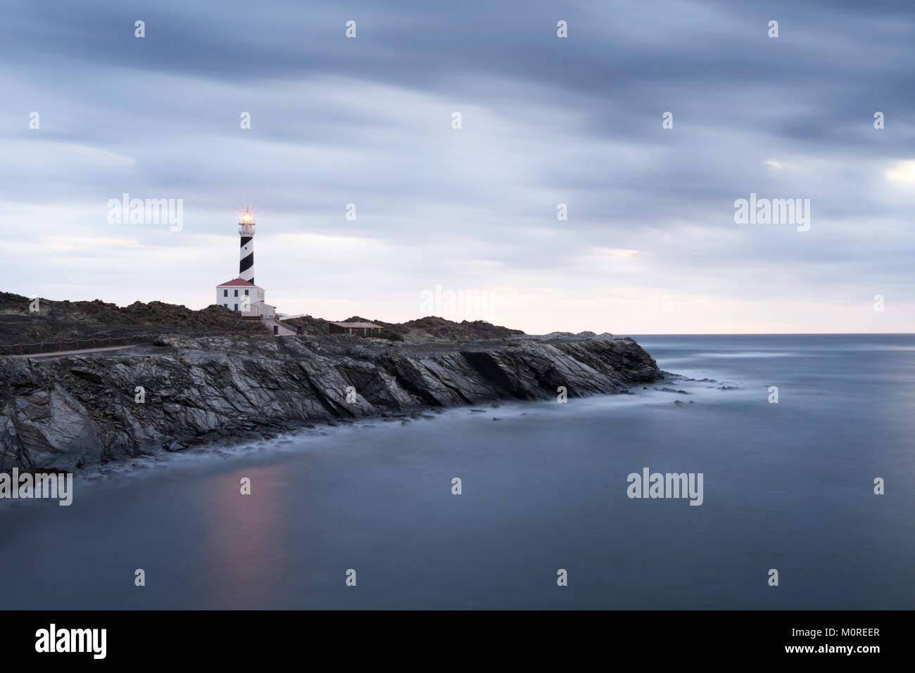 Long exposure shot of Favaritx lighthouse in a cloudy early morning at dawn. Menorca, Balearic Islands, Spain. Stock Photo